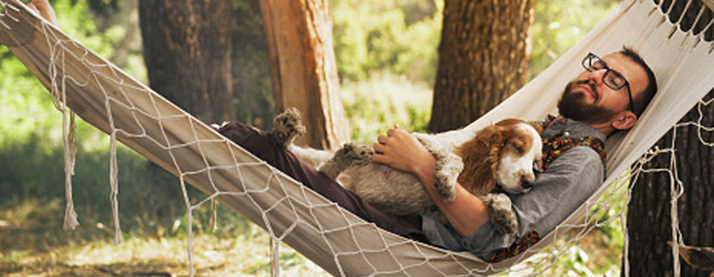 Man and dog relaxing in hammock.