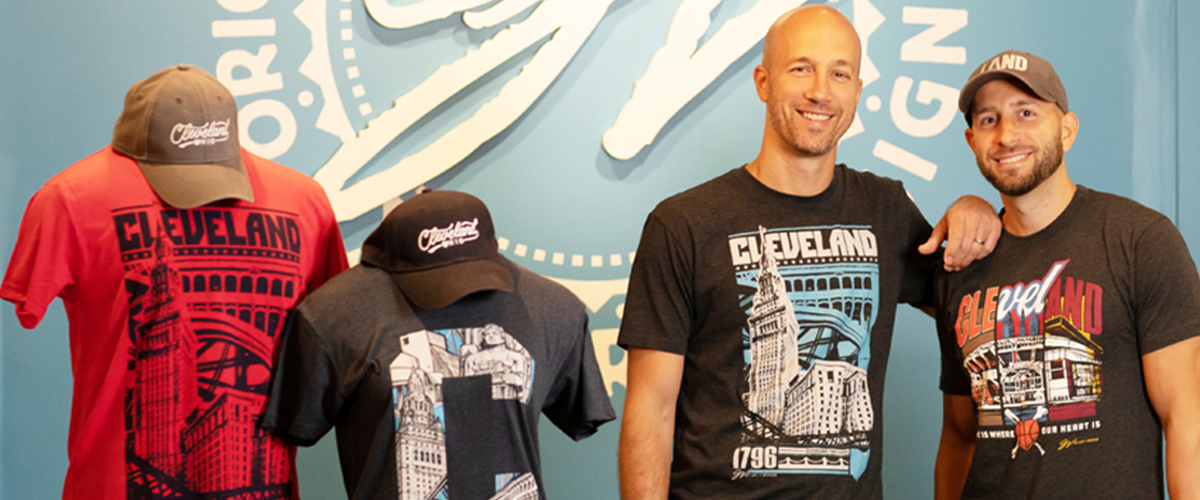 The two owners of "GV Art + Design" pose for a photo next to merchandise in their store.