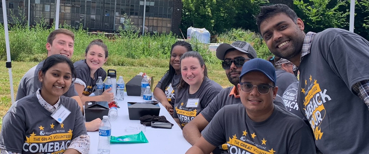 Group of Medical Mutual volunteers sitting around a table together outdoors.