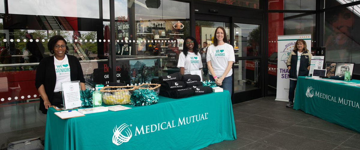 Medical Mutual employee volunteers stand at a vendor booth.