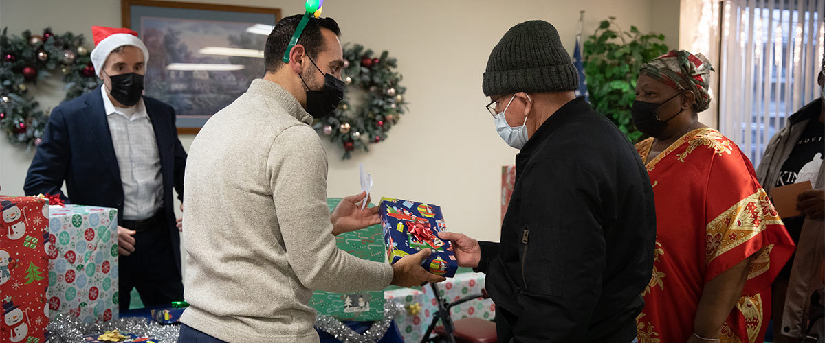 Man hands a wrapped gift over to another man.