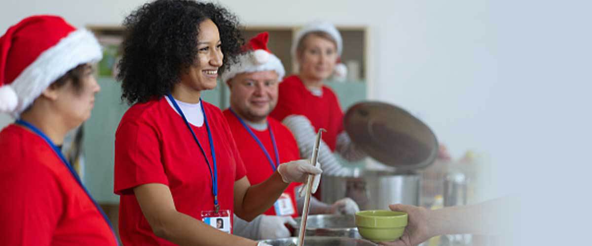 4 volunteers serve food in a soup kitchen.