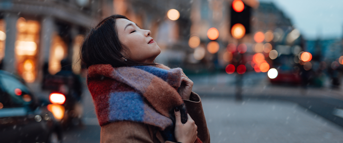 Woman taking a deep breath outdoors.