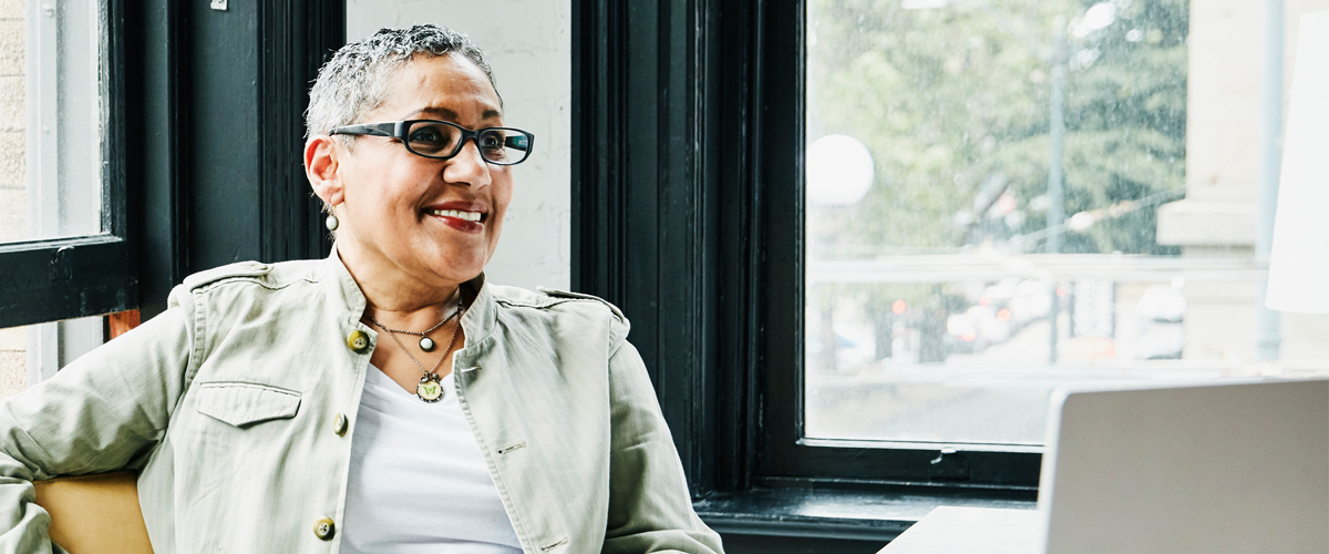 Woman smiling and looking at a laptop.
