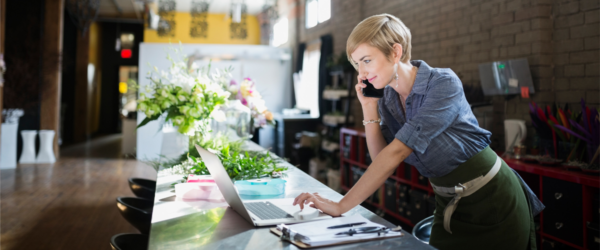 Woman on the phone while looking at her laptop.