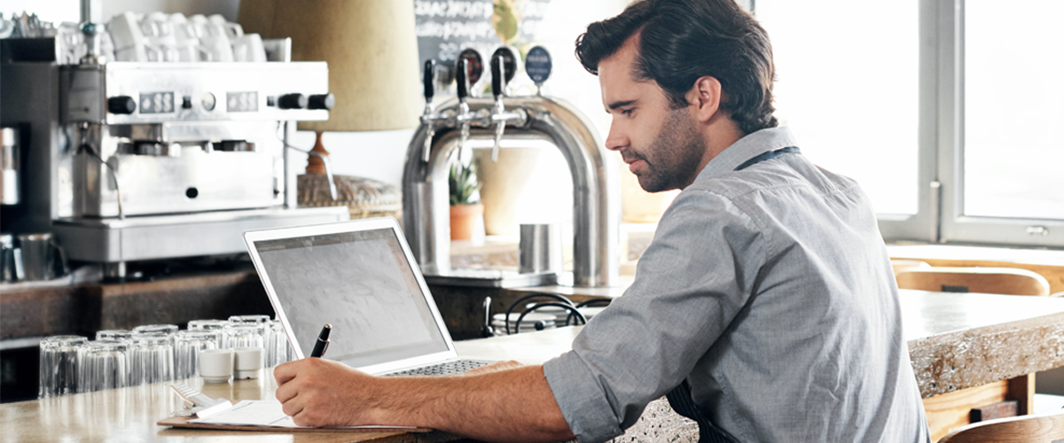 Man working in a coffee shop using a laptop.