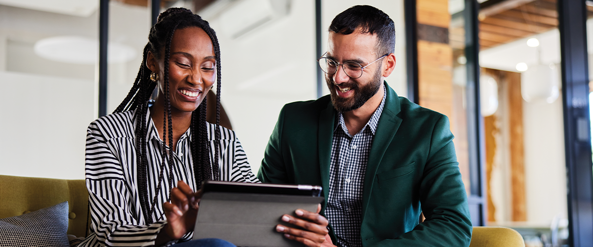 Man and woman in an office setting looking at a tablet.