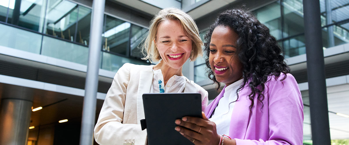 Two women looking at a tablet in an office setting.