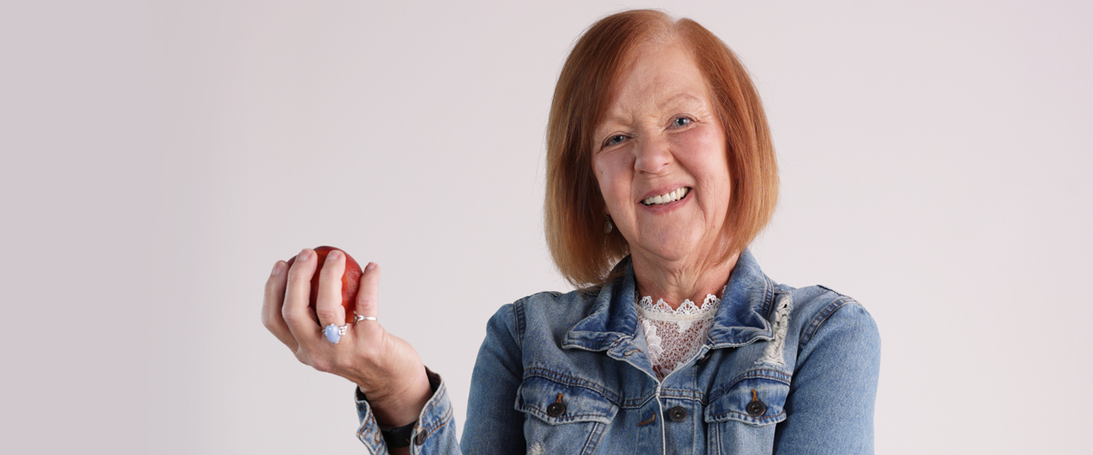 Woman smiling while holding an apple.