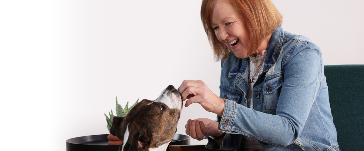 Senior woman feeding a dog.