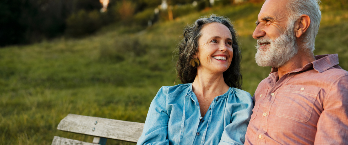 Older couple sitting on a bench outside.