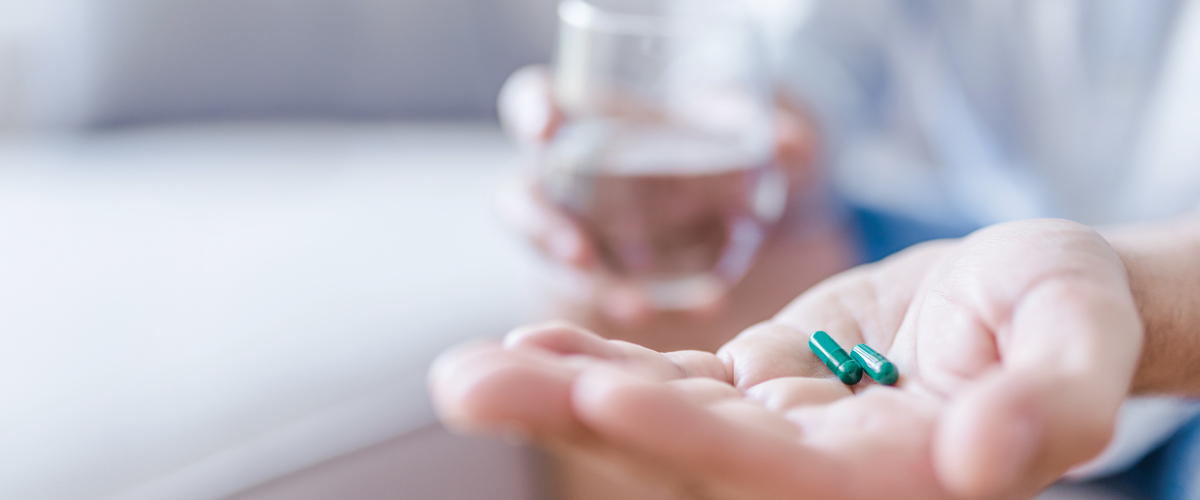 Close up of a hand holding two pills.