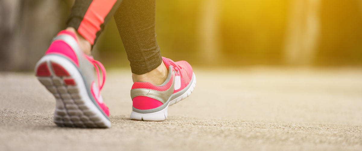 Close up of athletic shoes being worn by someone walking  outdoors.