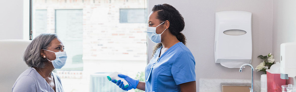 Medical professional taking a woman's temperature in a doctor's office.
