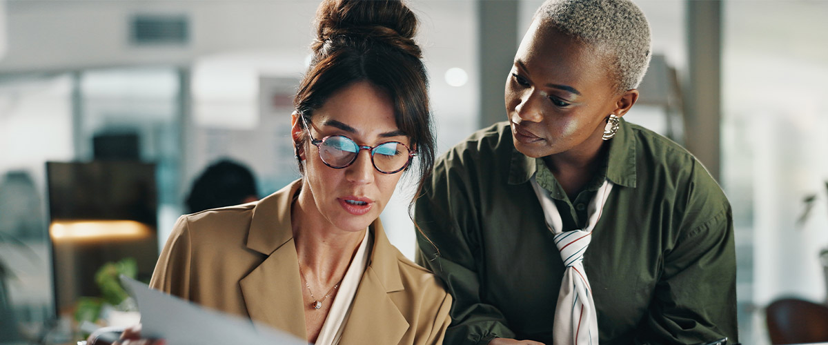 Two business professionals collaborating and reviewing information on a computer in a modern office.