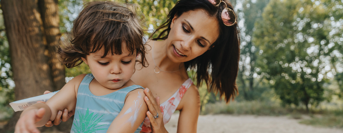 Woman applying sunscreen to a child's arm.