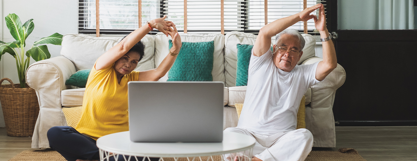 Photo of a man and woman stretching in front of a laptop.