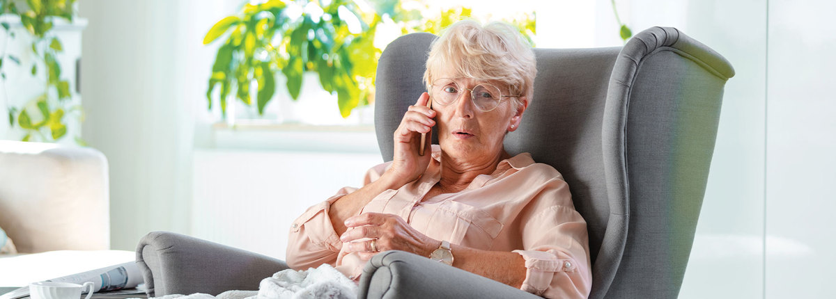 Older woman sitting in a chair while talking on the phone.