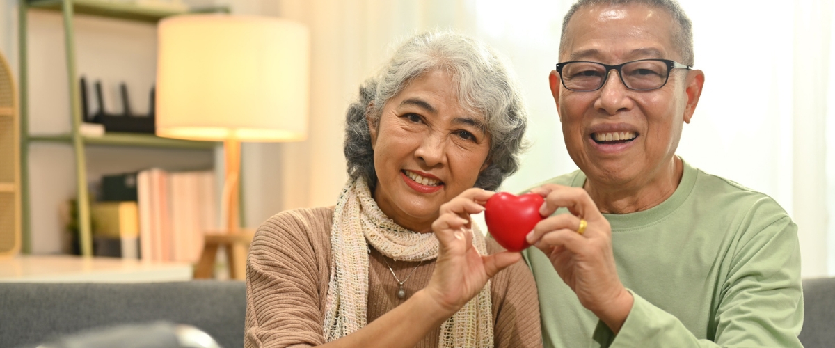 Senior couple holding a red heart.