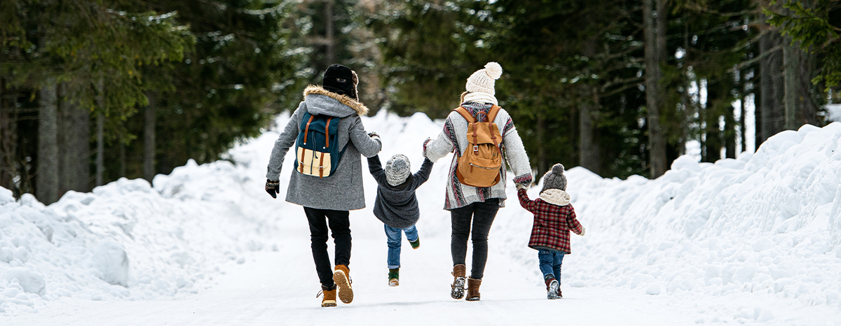 Family holding hands and walking through the snow.
